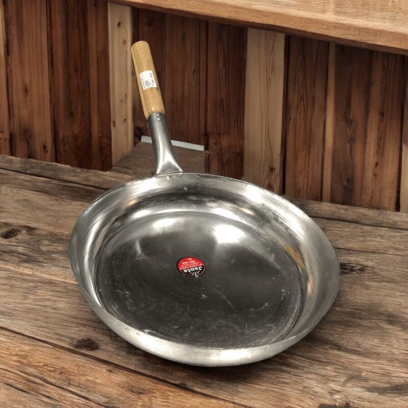 Janta Flat Iron Frying Pan with a sturdy wooden handle, available in 10-inch and 12-inch sizes, ideal for frying and cooking.