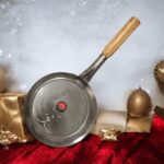 Janta Flat Iron Frying Pan with a sturdy wooden handle, available in 10-inch and 12-inch sizes, ideal for frying and cooking.