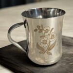 Mayur Gold Signature Stainless Steel Cup Set with a gold flower design, 250 ml capacity per cup, set of 4