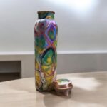 Beautifully engraved copper bottle with two matching floral design glasses, promoting health benefits like improved digestion and detoxification.