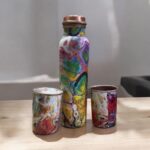 Beautifully engraved copper bottle with two matching floral design glasses, promoting health benefits like improved digestion and detoxification.