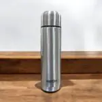 A high-quality Milton Flipstyle Thermosteel Flask (1000ml) with double-wall insulation, a leak-proof flip-top lid, and a protective thermal jacket, designed to keep beverages hot for long hours in cold weather.