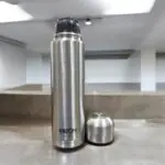 A high-quality Milton Flipstyle Thermosteel Flask (1000ml) with double-wall insulation, a leak-proof flip-top lid, and a protective thermal jacket, designed to keep beverages hot for long hours in cold weather.