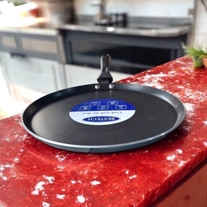 Non-stick black Bestech Dosa Tawa with induction base and thick 3mm bottom placed on a wooden kitchen table.