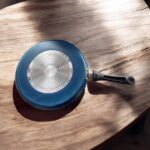 Non-stick black Bestech Dosa Tawa with induction base and thick 3mm bottom placed on a wooden kitchen table.