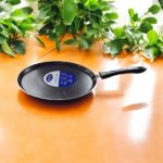 Non-stick black Bestech Dosa Tawa with induction base and thick 3mm bottom placed on a wooden kitchen table.