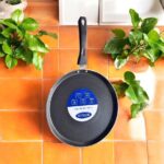 Non-stick black Bestech Dosa Tawa with induction base and thick 3mm bottom placed on a wooden kitchen table.
