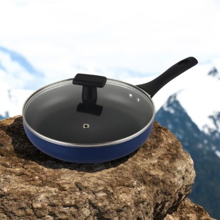 Blue non-stick induction fry pan with glass lid and long handle, shown on a modern kitchen counter; suitable for gas and induction stoves.