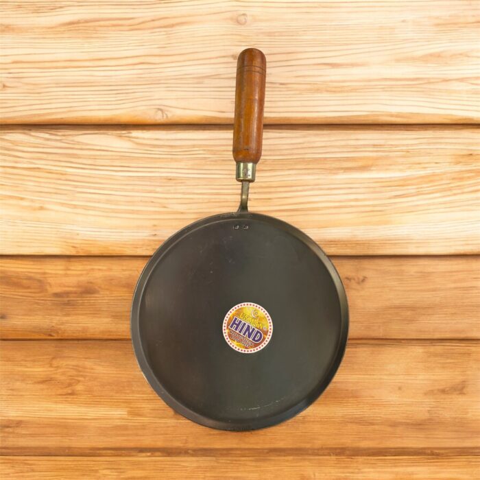 Flat 12-inch seasoned iron tawa with wooden handle for traditional Indian cooking – ideal for rotis, dosas, parathas, and cheelas.