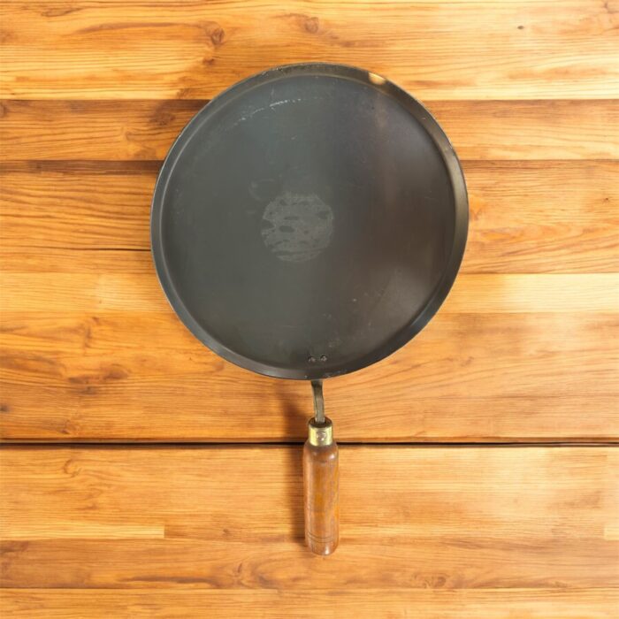 Flat 12-inch seasoned iron tawa with wooden handle for traditional Indian cooking – ideal for rotis, dosas, parathas, and cheelas.