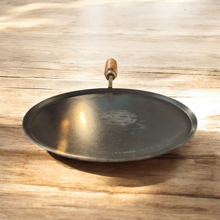 Flat 12-inch seasoned iron tawa with wooden handle for traditional Indian cooking – ideal for rotis, dosas, parathas, and cheelas.