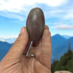 Partially buried Shakti Lingam idol representing Lord Shiva, crafted in natural stone and symbolizing divine grounding and cosmic energy.