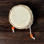 Pair of traditional wooden Damrus with white cords and red detailing, representing the rhythm of Lord Shiva
