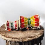 Pair of traditional wooden Damrus with white cords and red detailing, representing the rhythm of Lord Shiva