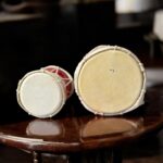 Pair of traditional wooden Damrus with white cords and red detailing, representing the rhythm of Lord Shiva