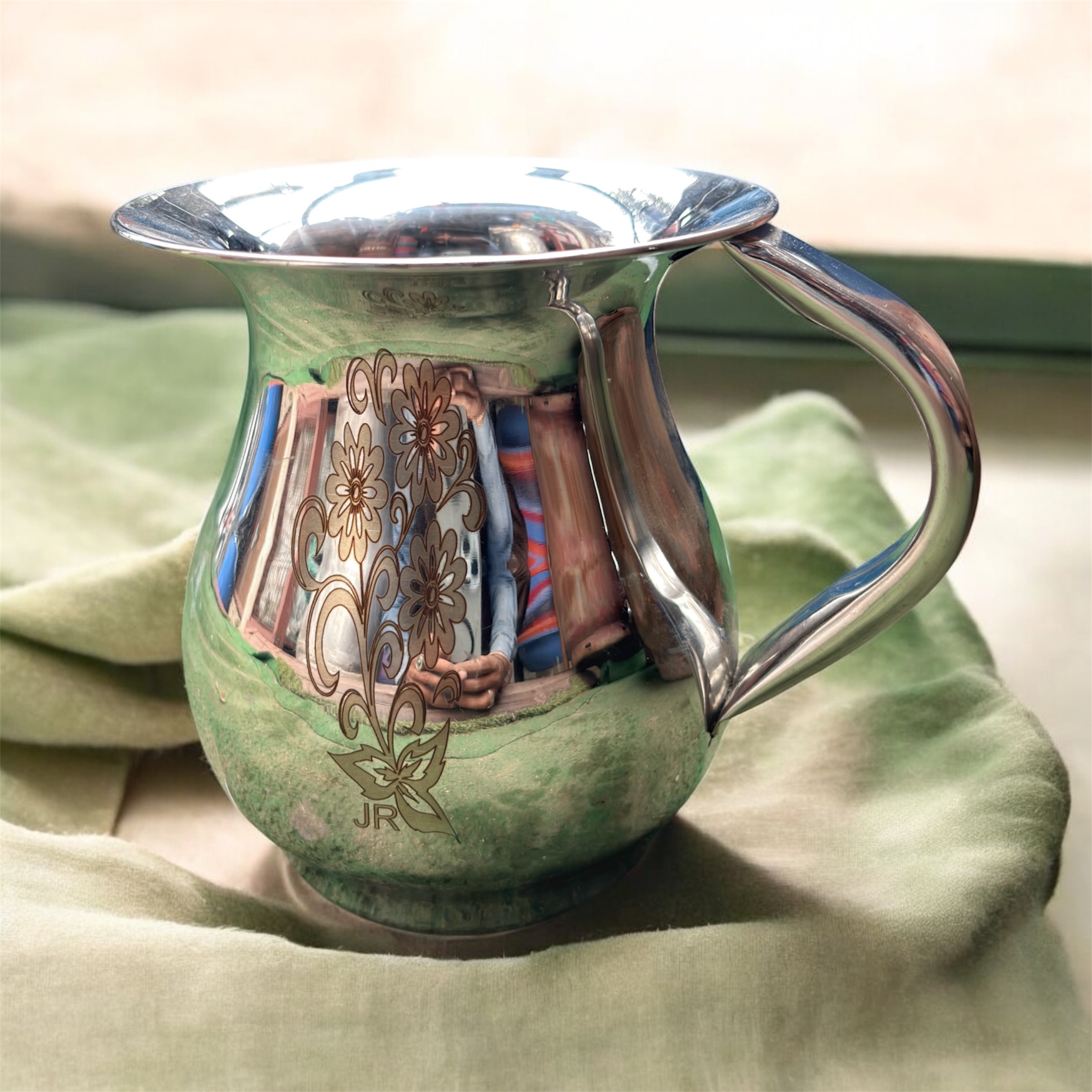A compact 500 ML stainless steel jug with intricate floral etching, showcasing a traditional Indian design, perfect for daily hydration or pooja rituals.