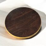 A round hardboard chakla with a dark brown top surface and yellow edges, featuring three anti-slip base supports, placed on a rustic wooden surface.A round hardboard chakla with a dark brown top surface and yellow edges, featuring three anti-slip base supports, placed on a rustic wooden surface.