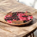 Designer floral print hardboard rolling board chakla with red flowers on a black background, used for roti preparation.
