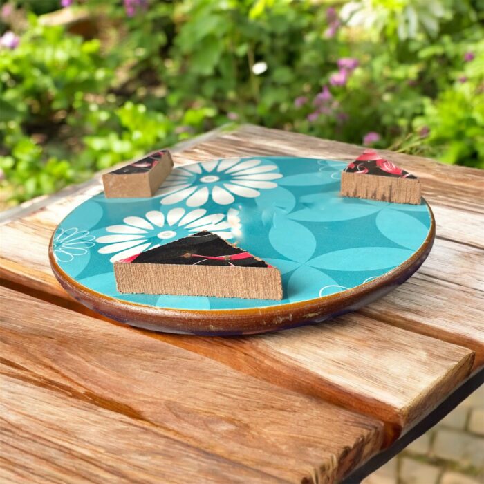 Designer floral print hardboard rolling board chakla with red flowers on a black background, used for roti preparation.