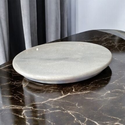 A round, natural white marble roti chakla with a smooth finish, perfect for rolling rotis and puris while adding an elegant touch to any kitchen.