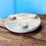 A white marble chakla with a smooth finish and anti-slip rubber base, ideal for rolling rotis and puris on any kitchen surface.