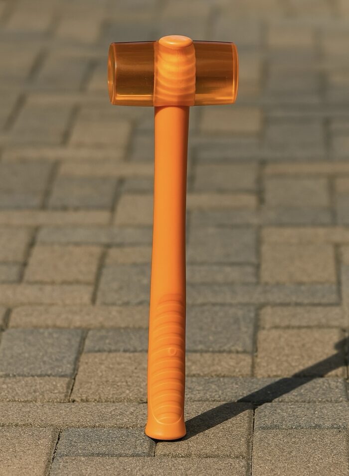 Orange rubber mallet hammer placed on wooden planks beside work gloves and tools, ideal for woodworking, carpentry, and furniture assembly – RRS ShockGuard™ 50mm/60mm.