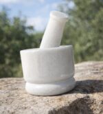 Solid white marble mortar and pestle set (4 inch khal batta) used for grinding spices, herbs, and Ayurvedic ingredients in a traditional kitchen setting.