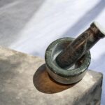 Natural stone mortar and pestle (khal batta) 4 inch wide with 4.5 inch pestle for grinding spices, herbs, and pooja materials in traditional kitchen setting.