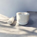 Solid white marble mortar and pestle set (4 inch khal batta) used for grinding spices, herbs, and Ayurvedic ingredients in a traditional kitchen setting.