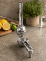 RuliaRams metal lemon squeezer with silver finish, 7.5 inch heavy duty citrus press placed on kitchen counter with fresh lemon