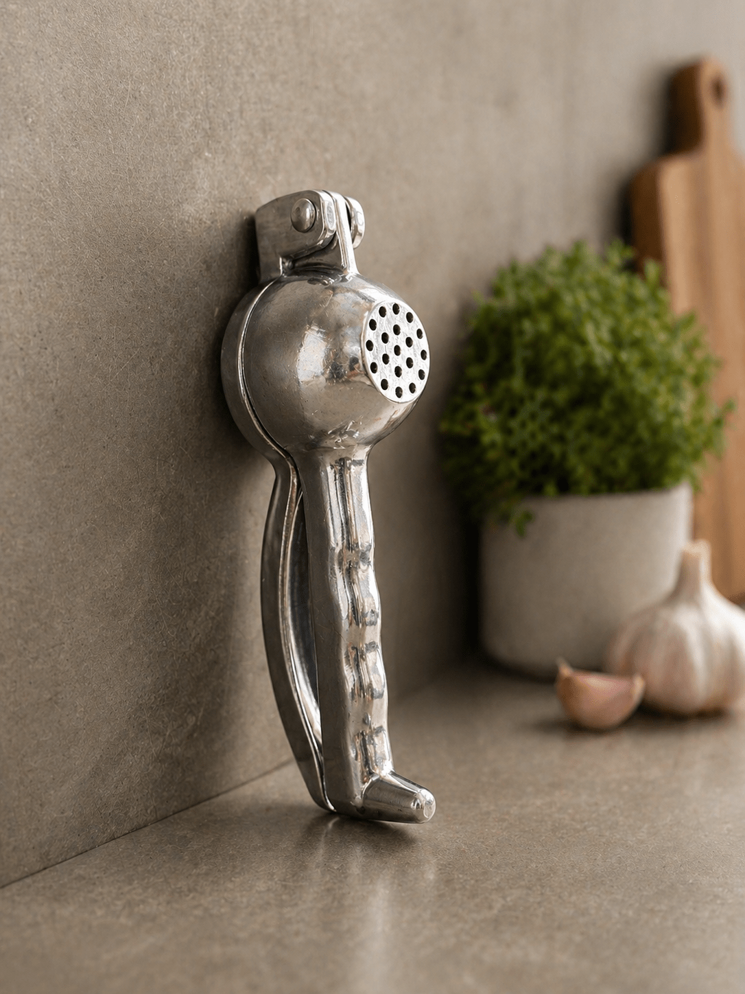 RuliaRams metal lemon squeezer with silver finish, 7.5 inch heavy duty citrus press placed on kitchen counter with fresh lemon