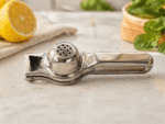 Premium stainless steel lemon squeezer by Neelu, 7.5 inch manual citrus juicer placed on wooden board with fresh lemon in background