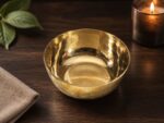 Rulia Rams Heritage Bronze Bowl™ – 6.2 Inch mirror-polished handcrafted bronze bowl with a luxurious golden finish, displayed on a wooden table. Premium Kansa dining bowl designed for traditional dining, Ayurvedic lifestyle, and elegant home décor.